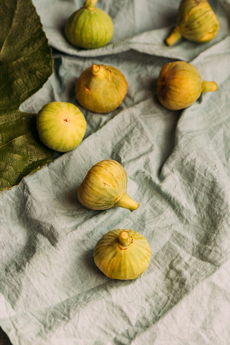 Reife süße grüne Feigen, frisch geerntet von einem heimischen Baum, auf dem pastellblauen Tischtuch. Gesundes und biologisches Obst. Auch bekannt als reife weiße Feigen