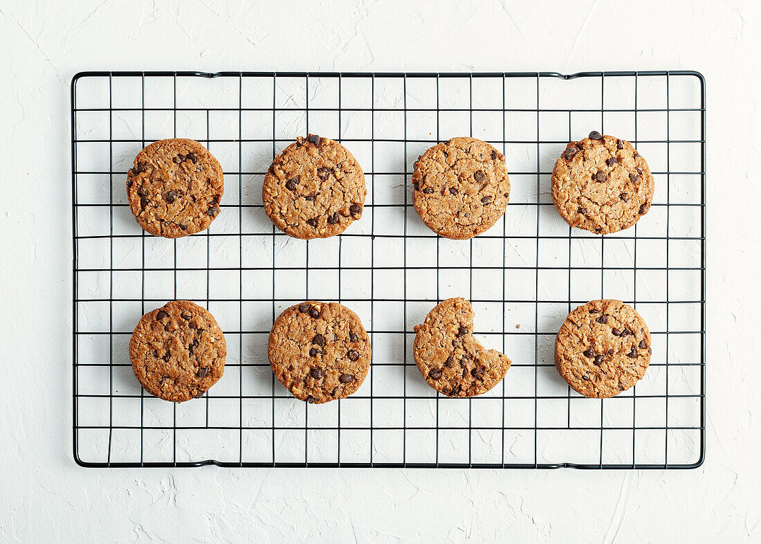 Top view of tasty homemade sweet cookies with chocolate chips placed on metal cooling rack on white background in kitchen