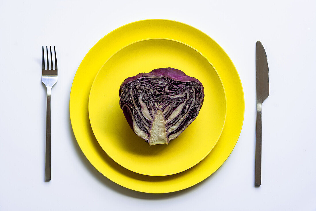 Von oben halbierter Rotkohl auf gelben Tellern auf weißem Hintergrund