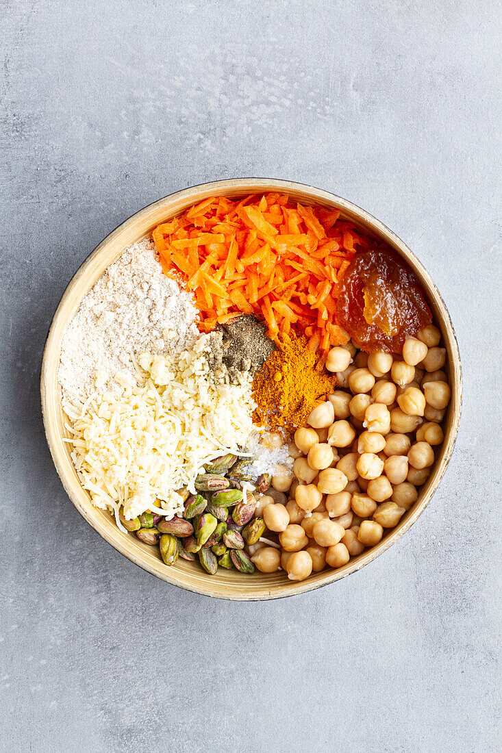 Schüssel mit Zutaten für Veggie-Curry und Mango-Chutney-Burger mit Kichererbsen, Karotten und Käse mit Gewürzen und Semmelbröseln, von oben gesehen