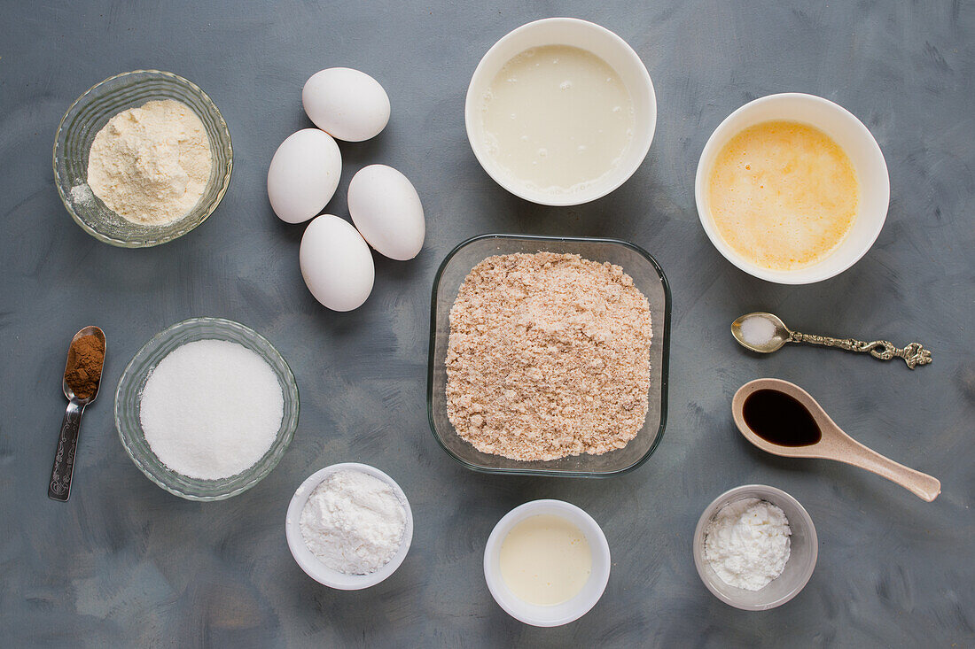 Top view of various ingredients for healthy keto coffee muffins with flour and egg placed on gray background with sweetener