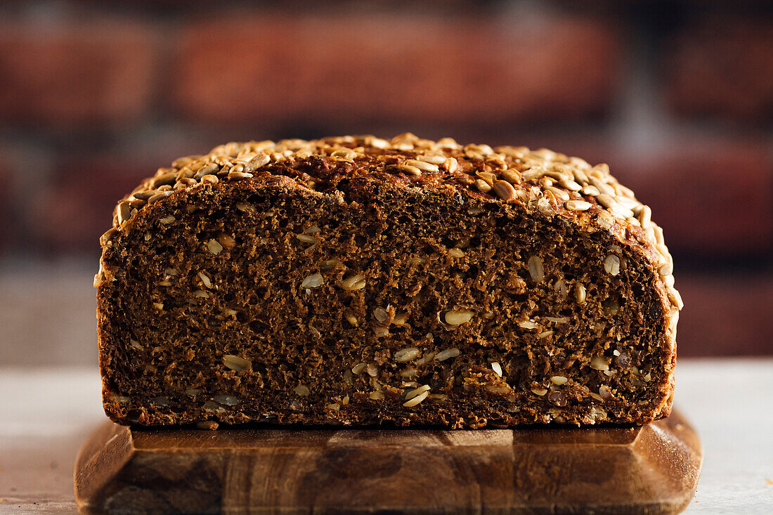 Leckeres Vollkornbrot auf Schneidebrett auf Tisch