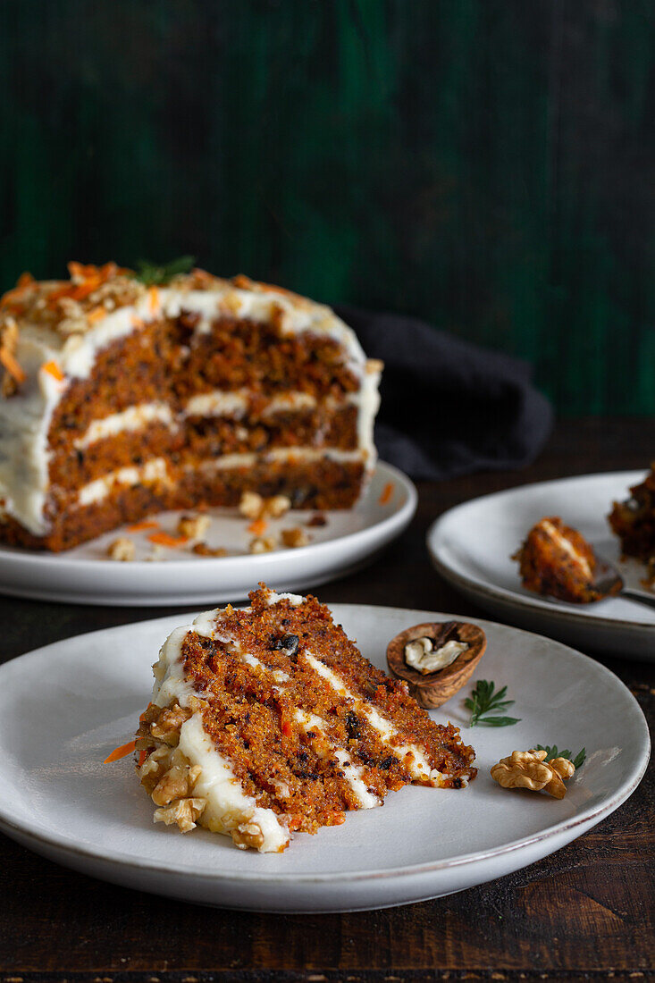 Leckerer Kuchen mit Frischkäse, serviert auf Tellern mit frischen Karottenscheiben und Walnüssen