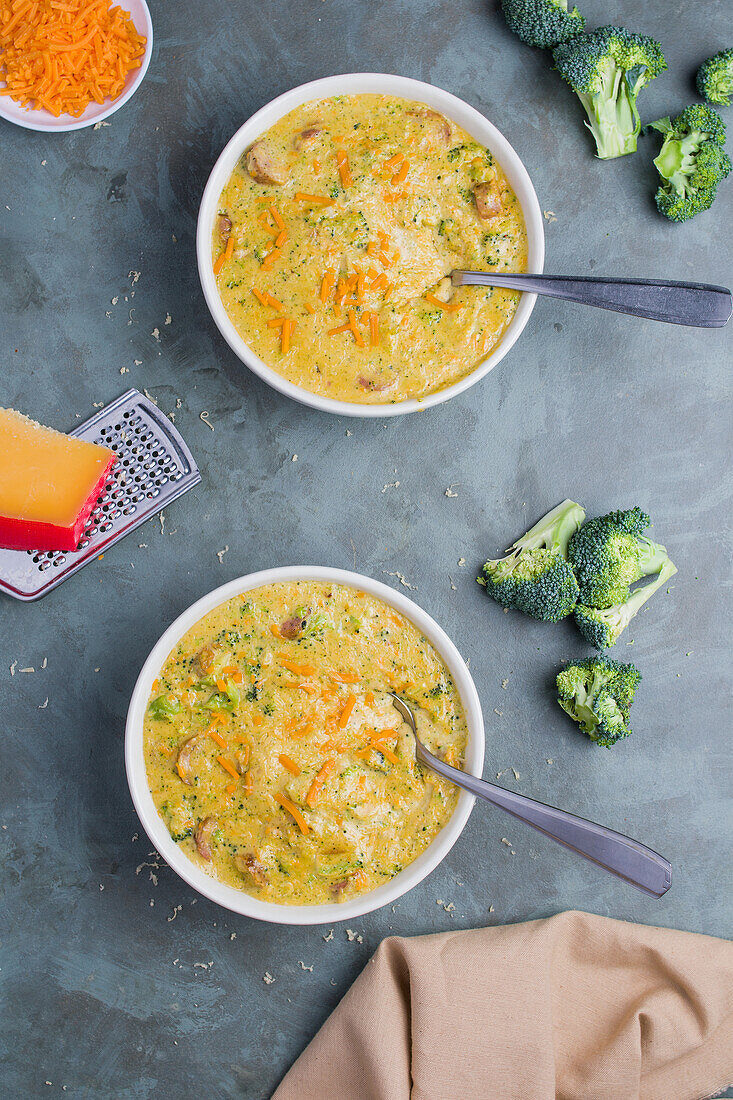Draufsicht auf Schalen mit leckerer Suppe mit Brokkoli und Käse auf grauem Tisch im Restaurant