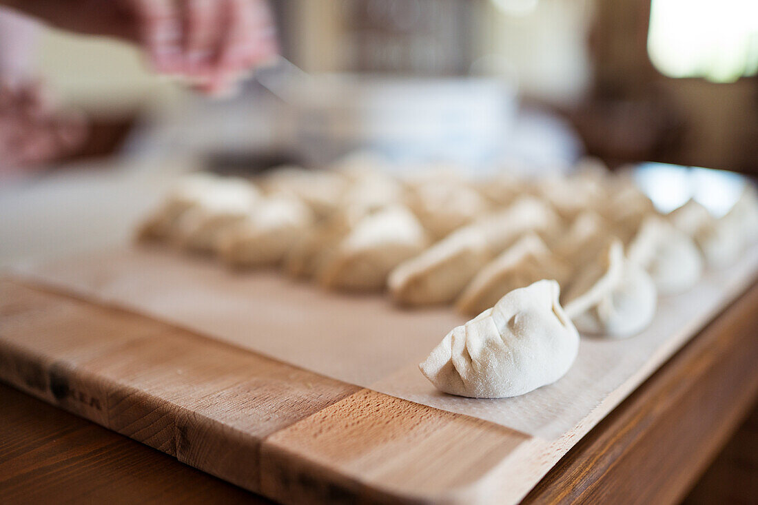 Von oben gesehen rohe traditionelle Jiaozi-Klöße, die auf einem hölzernen Schneidebrett in der Küche serviert werden