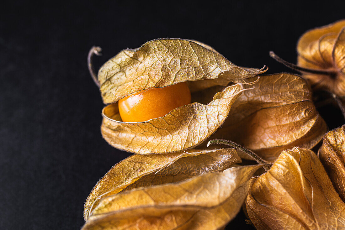 Exotische orangefarbene peruanische Erdkirsche auf schwarzem Tisch im Studio