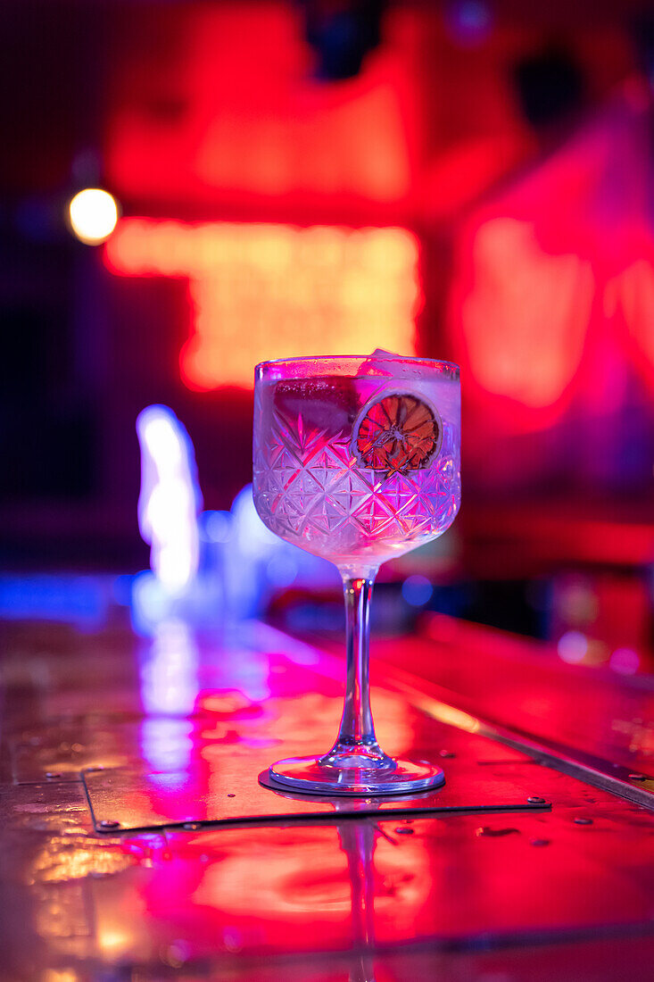 Gut durchdachter Gin-Tonic-Cocktail, dekoriert mit Erdbeeren und trockener Zitronenscheibe in einer Bar