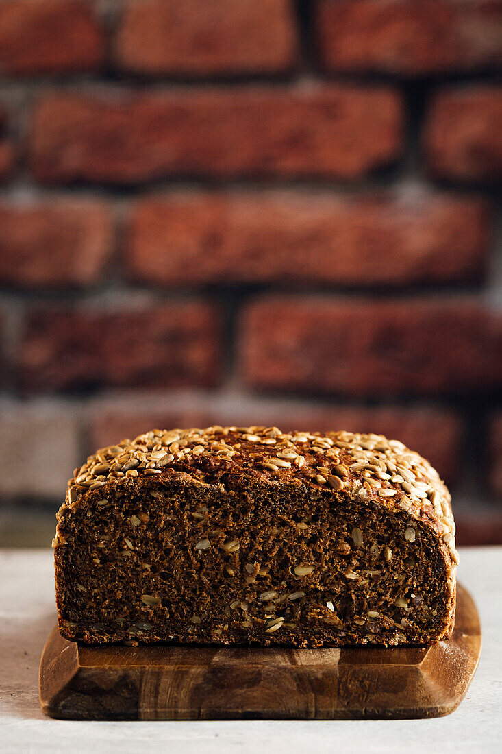 Leckeres Vollkornbrot auf Schneidebrett auf Tisch