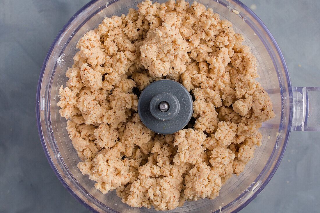 From above blender bowl with dough while preparing pie