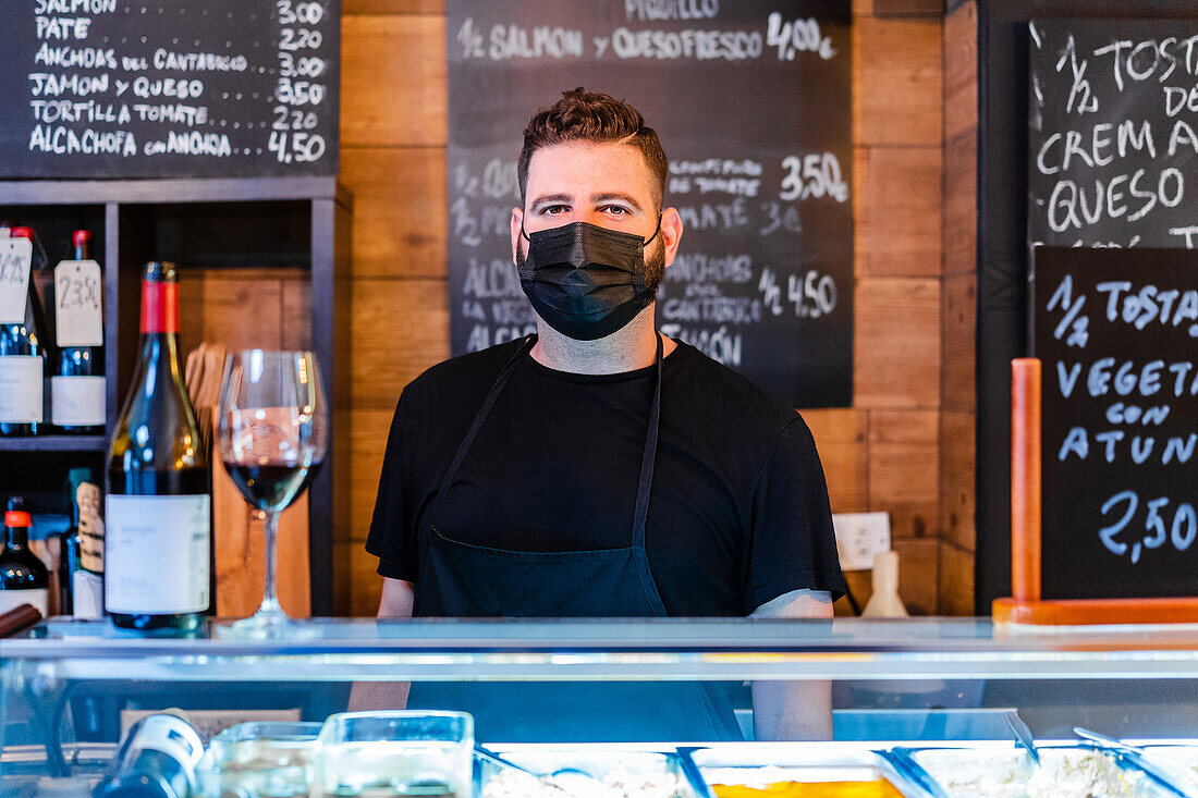 Barkeeper neben Weinflasche auf Tresen in Restaurant mit vielen Schildern