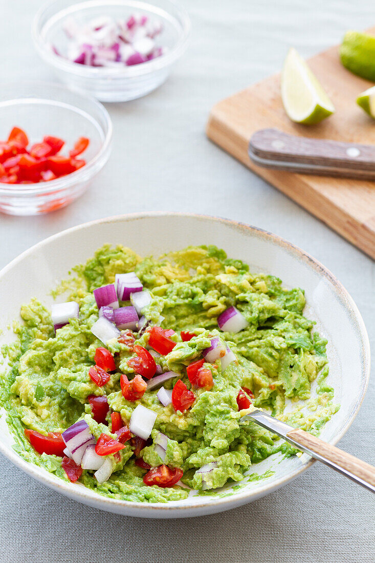 Leckere Guacamole mit frischen roten Zwiebelscheiben in einer Keramikschale auf dem Tisch von oben