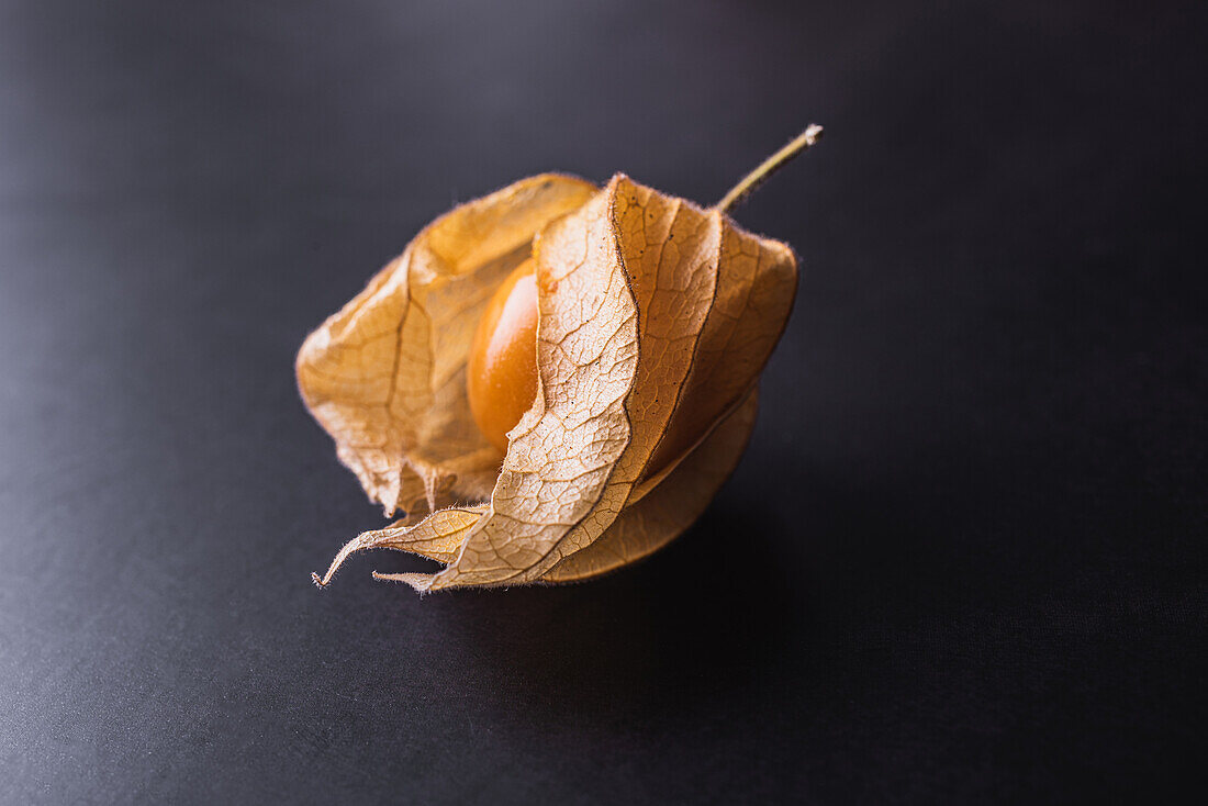 Exotische orangefarbene peruanische Erdkirsche von oben auf schwarzem Tisch im Studio