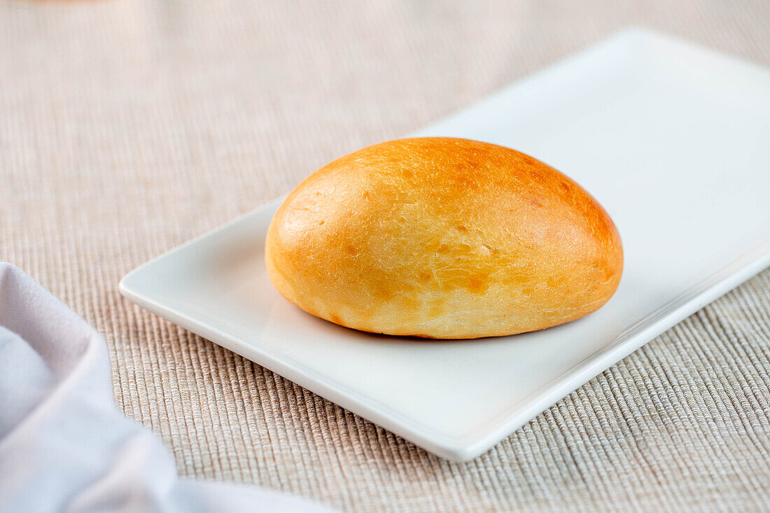 High angle of delicious freshly baked bun served on rectangular plate in morning at home