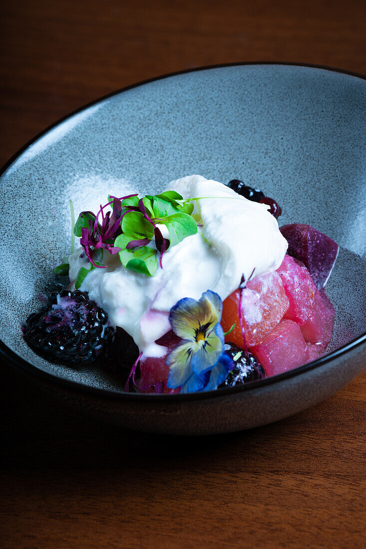 Creamy Stracciatella cheese atop a vibrant beetroot and berry salad, garnished with edible flowers.