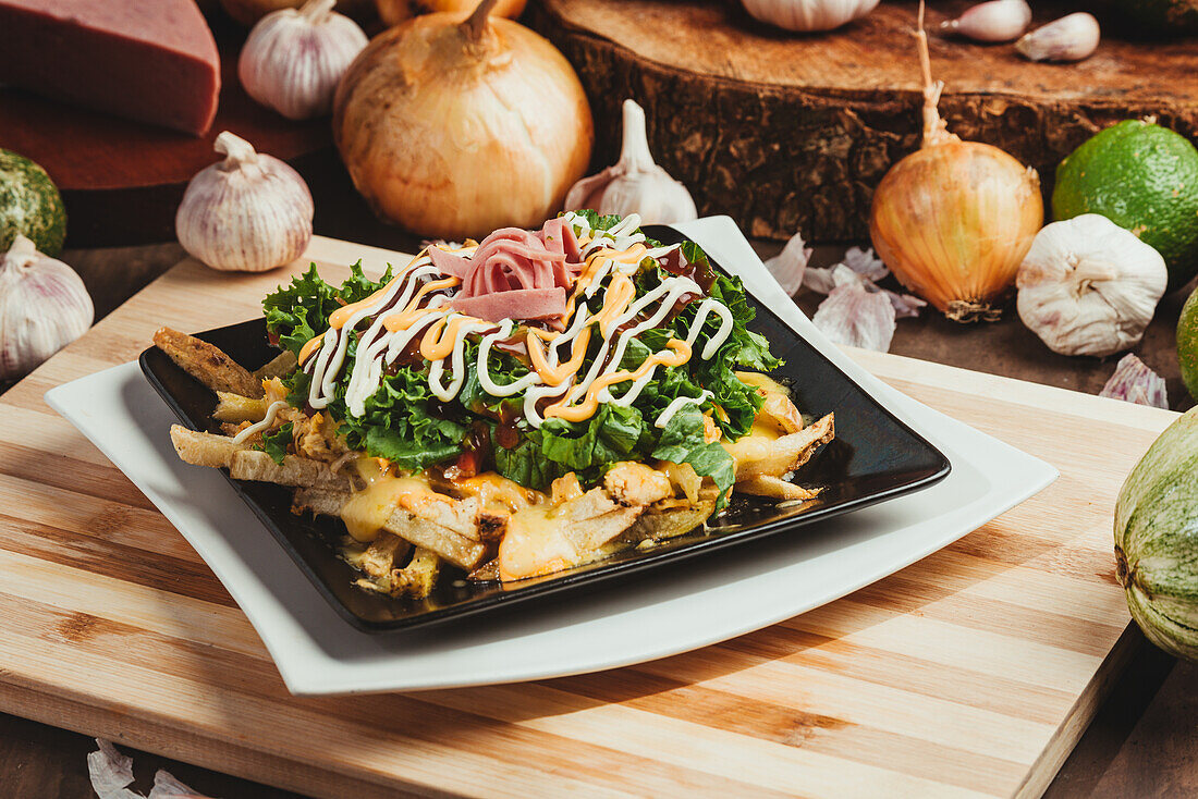 Leckere Pommes frites mit frischem Salat und Schinken unter Soßen auf einem Teller auf dem Tisch