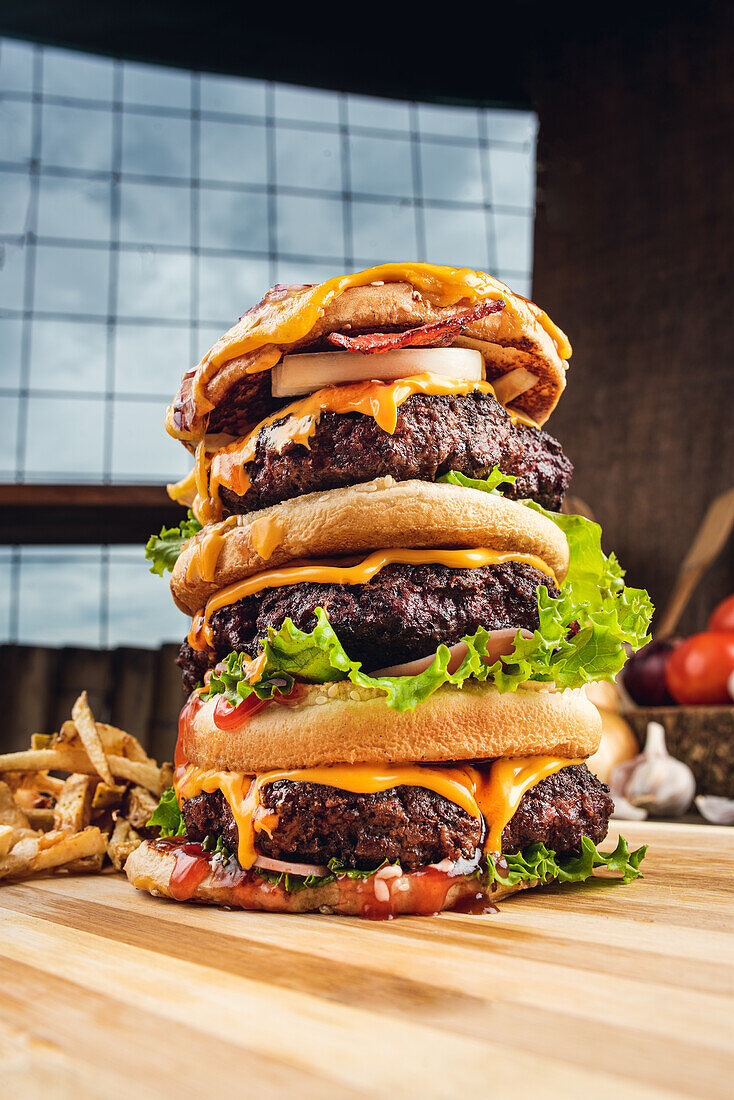 Appetitliche Hamburger mit Gemüse auf Holzbrett mit Pommes frites in Küche