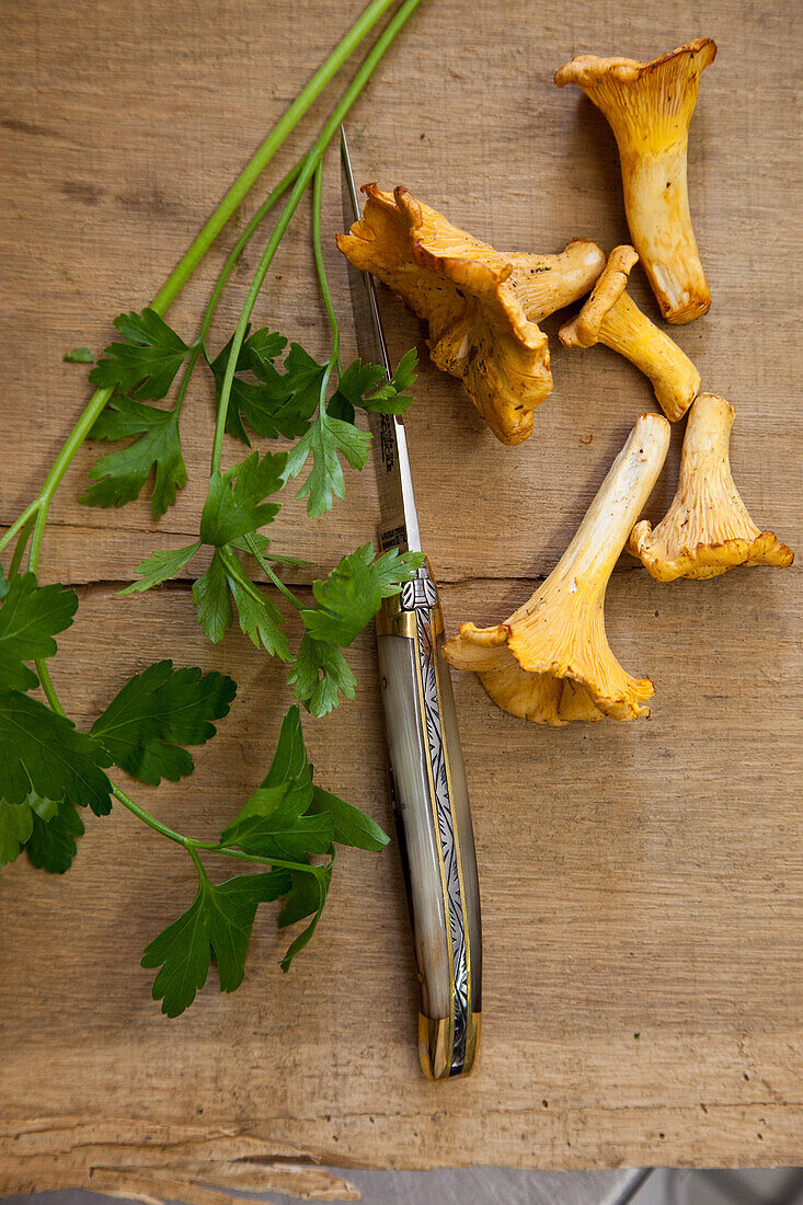 Pfifferlinge und Petersilie auf Holzbrett