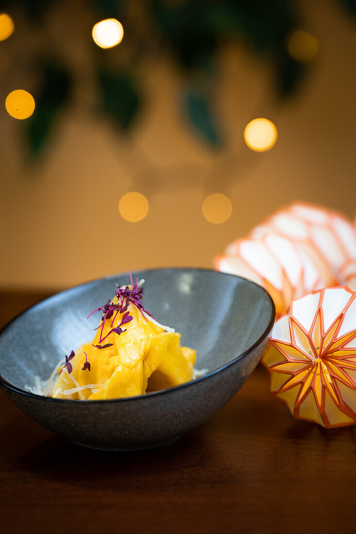 Cheese and walnuts tortellini in a bowl, adorned with a delicate edible flower garnish.