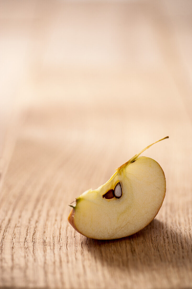 Whole apple and apple wedge on wooden table