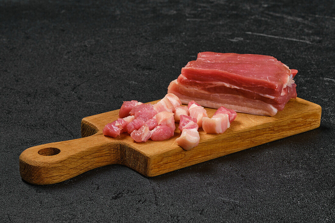 Raw pork belly on a wooden board, partially sliced