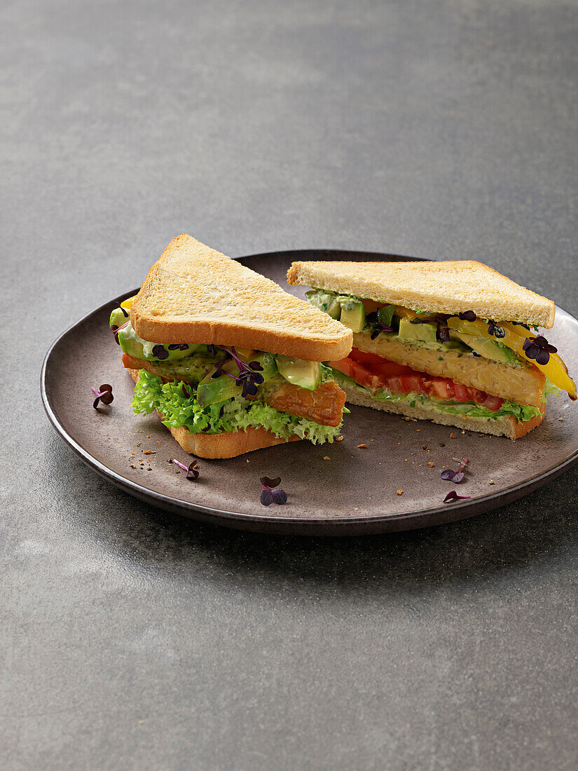 Sandwich mit Tempeh, Avocado, Tomaten und Kräutern