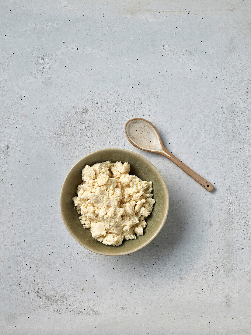 Bowl of fresh cottage cheese and wooden spoon