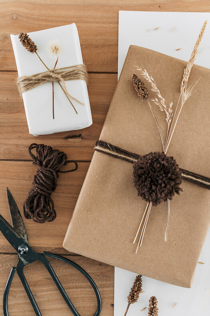 Geschenkverpackungen mit getrockneten Gräsern und Pompons