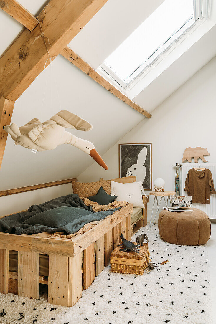 Kinderzimmer mit DIY-Holzbett, kuscheligem Teppich und Dachfenster