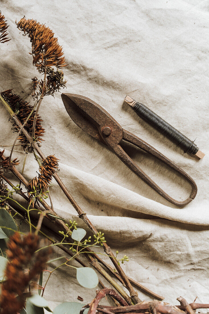 Antique secateurs and binding wire on linen cloth with dried flowers