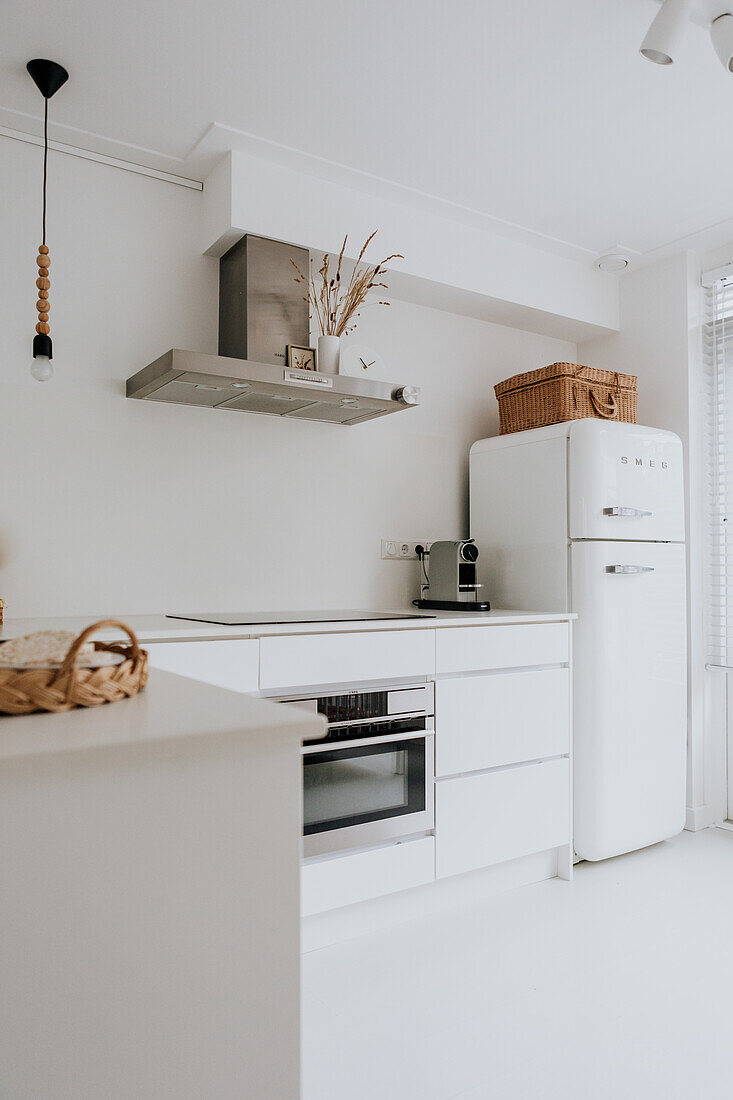 Moderne weiße Küche mit integriertem Backofen und Retro-Kühlschrank