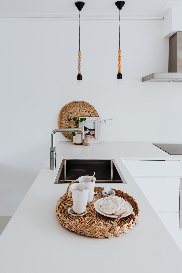 Modern kitchen with white worktop, sink and rattan tray