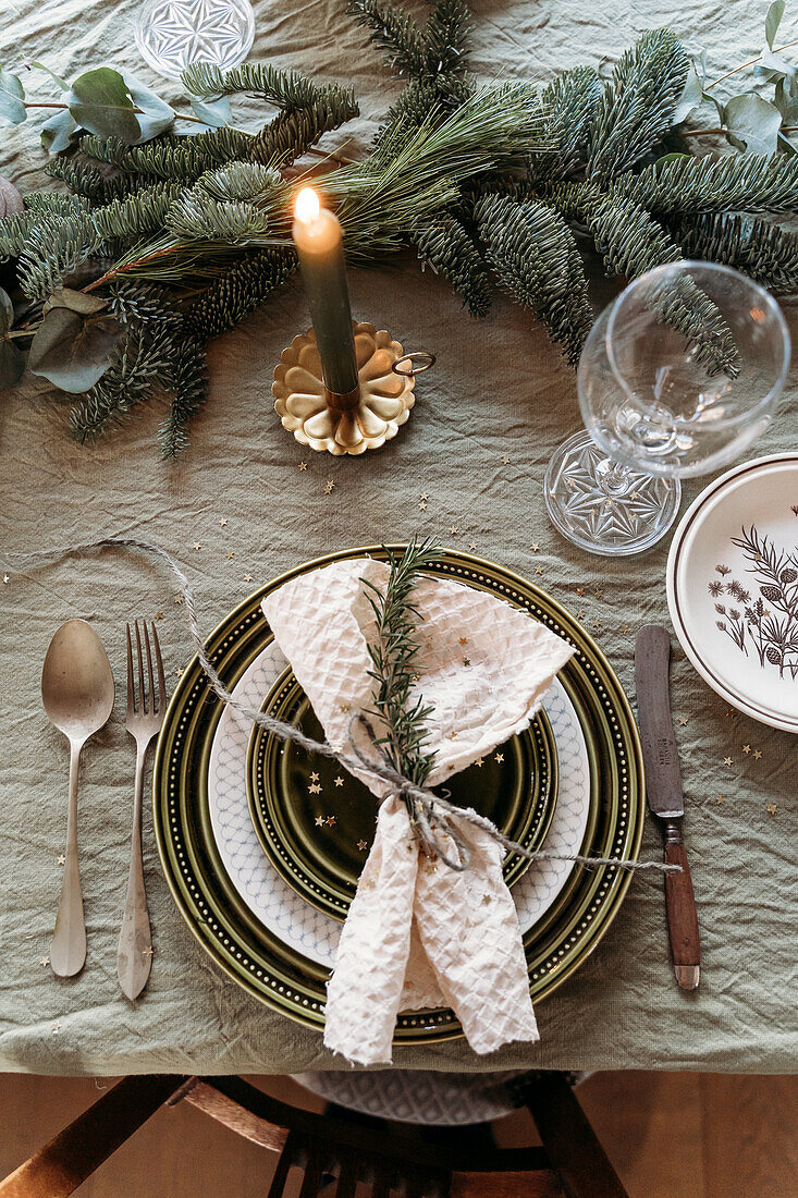 Weihnachtlich gedeckter Tisch mit Kerze und Tannenzweigen