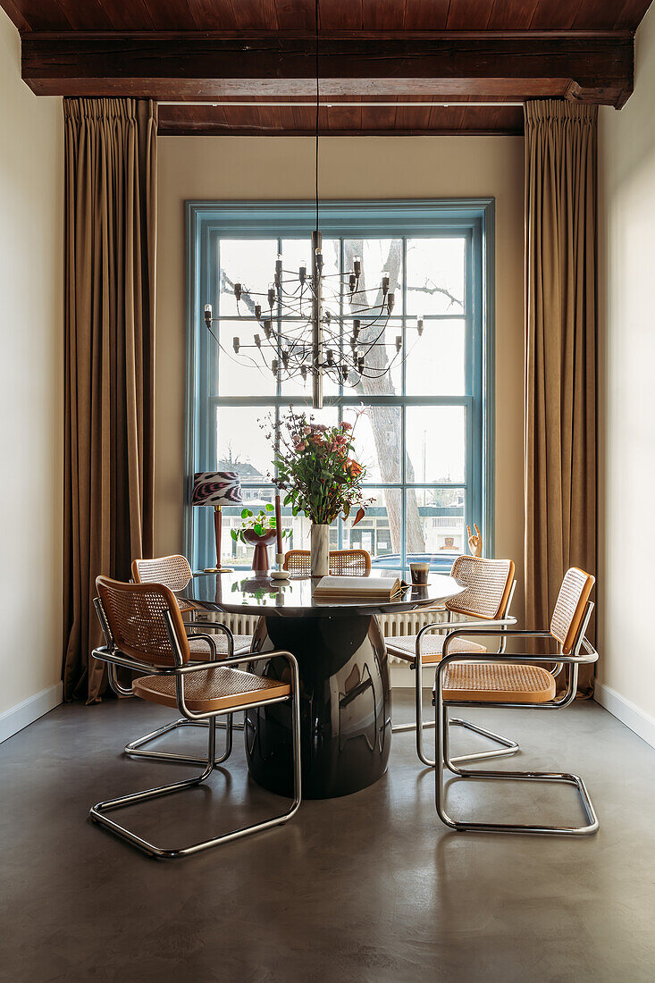 Dining area with round table and cantilever chairs in front of floor-to-ceiling window