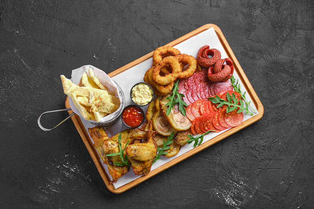 Snack-Platte mit Fleisch, Wurst, Zwiebelringen und Dips