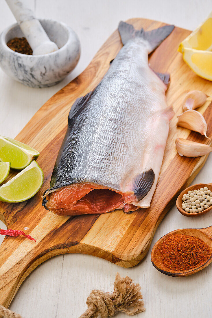 Raw salmon on a chopping board with lime and spices