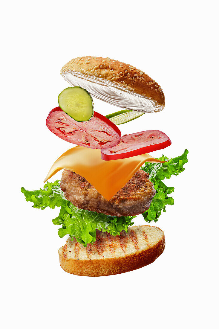 Burger with flying ingredients: Bun, lettuce, tomato, cheese, meat and cucumber