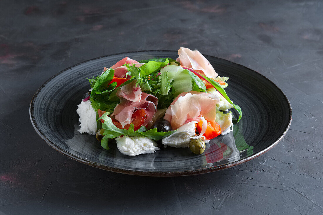 Fresh salad with jamon, mozzarella, tomatoes and olives