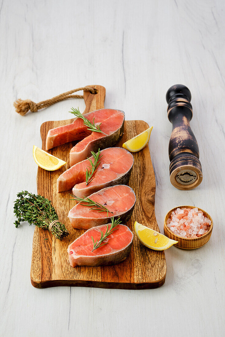 Raw salmon steaks with lemon wedges and herbs