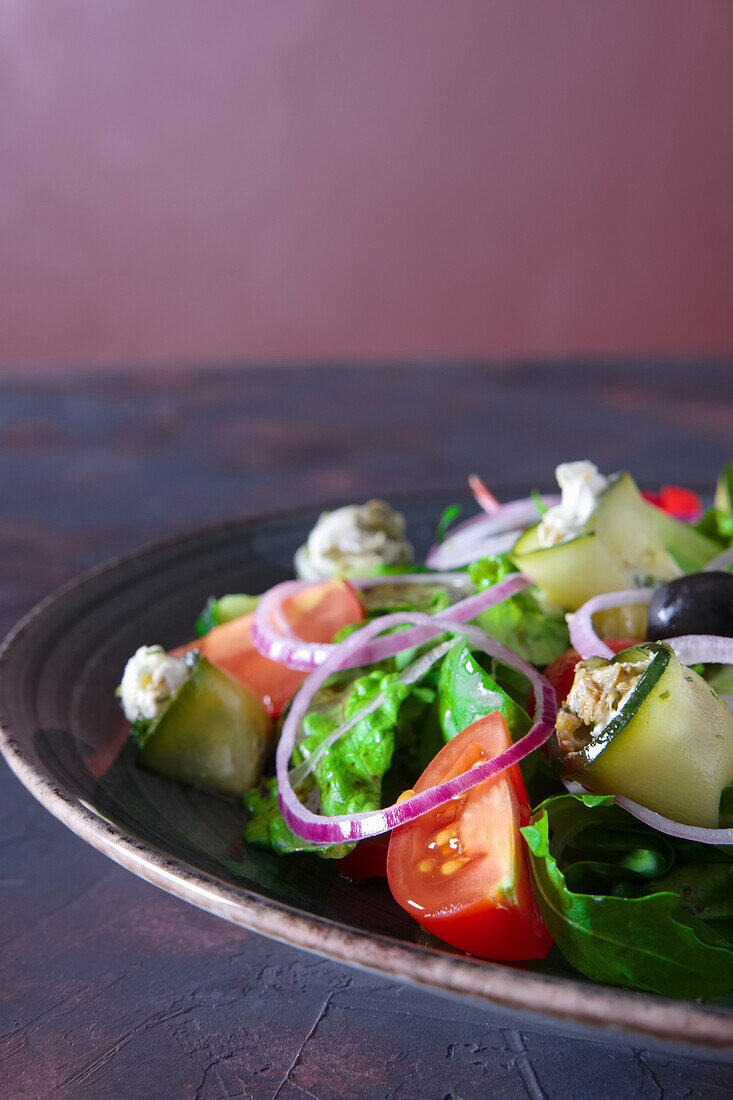 Fresh salad with stuffed courgette rolls, tomatoes and olives