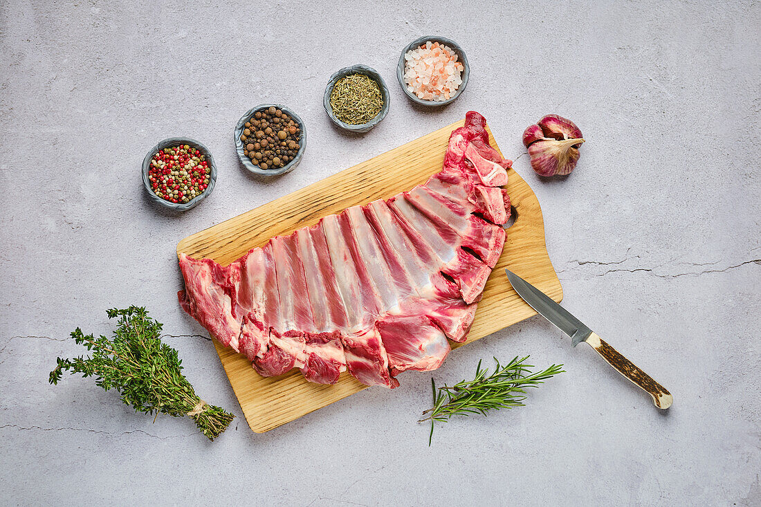 Raw venison ribs with herbs and spices on a wooden board