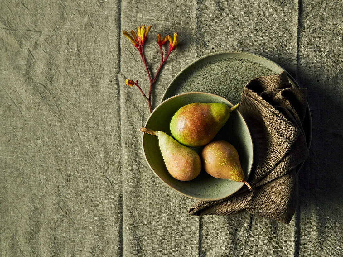 Three pears in a bowl on linen cloth