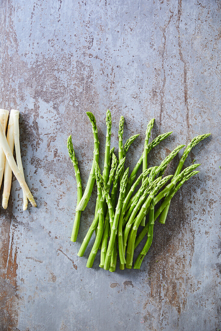 Green and white asparagus on metal surface