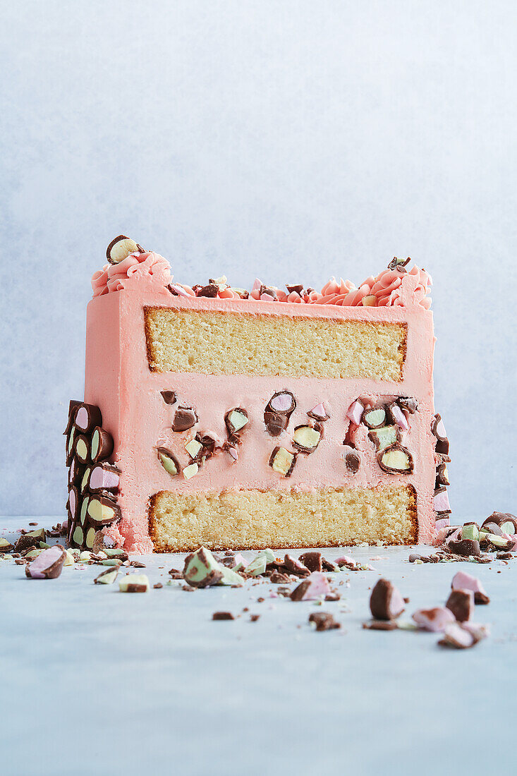 Schichttorte mit rosa Buttercreme und bunten Schokostücken