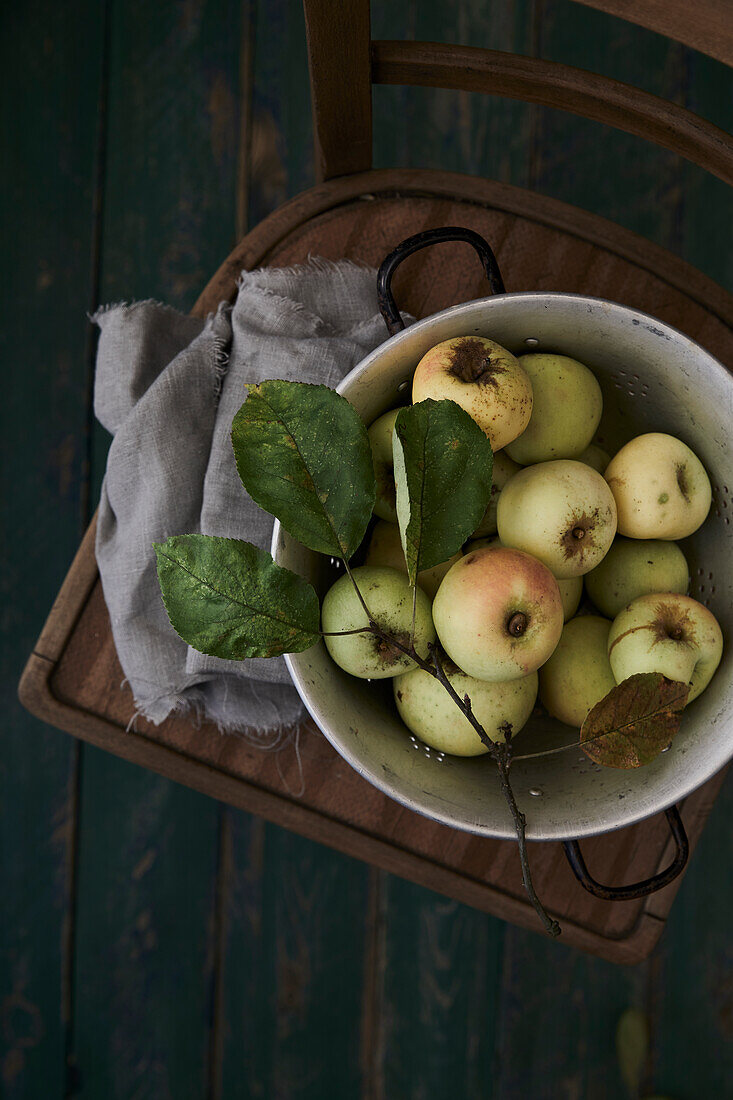 Apples in a sieve with twigs and leaves