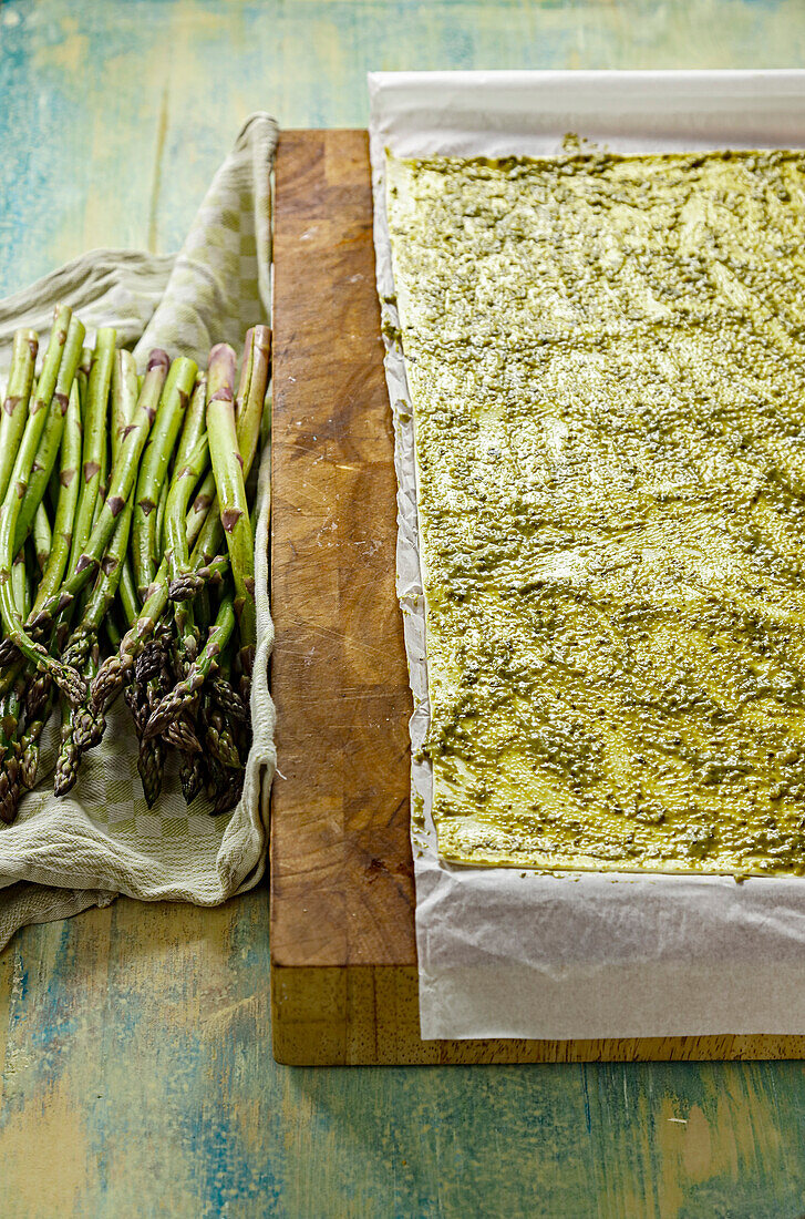 Preparing asparagus in puff pastry; pastry coated with pesto