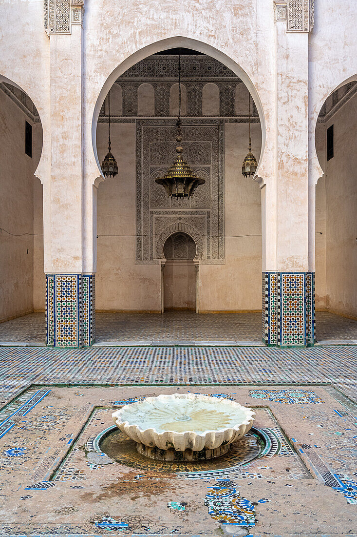 Ruhiger Innenhof mit einem traditionellen Brunnen und kunstvollen Fliesen in Fez, Marokko.