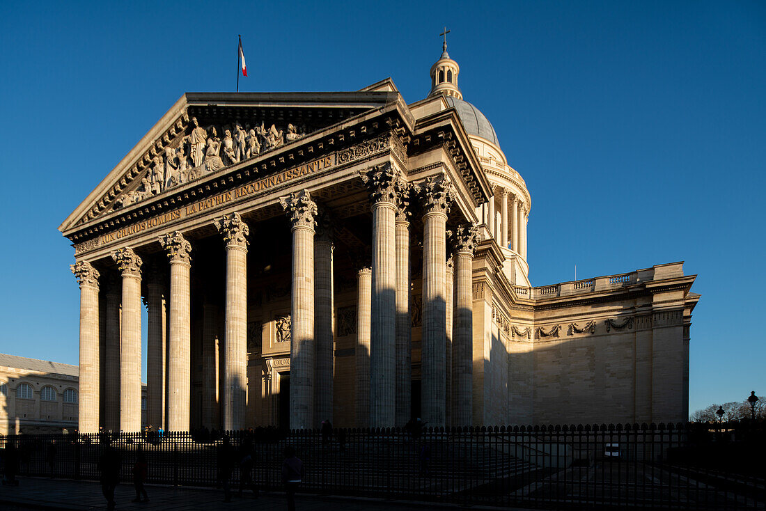 Die untergehende Sonne wirft Schatten auf die große neoklassizistische Fassade des Panthéons in Paris.