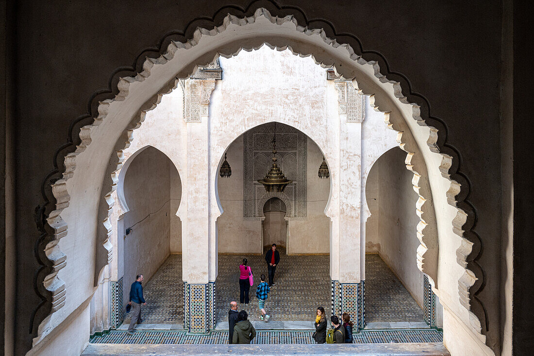 A tranquil view captures the essence of Fez through the ornate window of Cherratine Madrasa. Fez, Morocco.