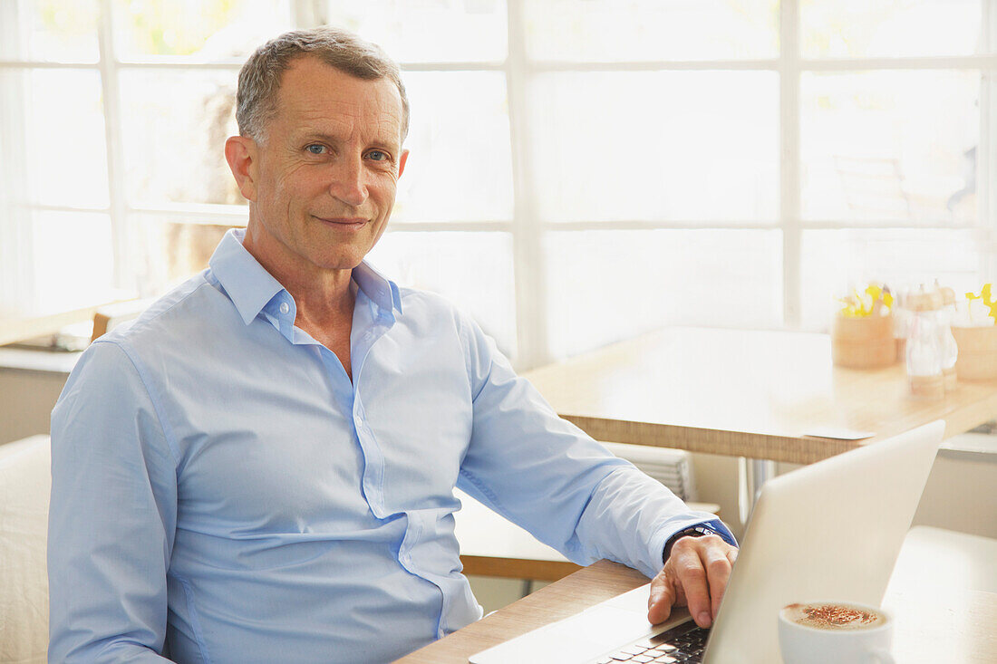 Mature Man Using Laptop in Cafe