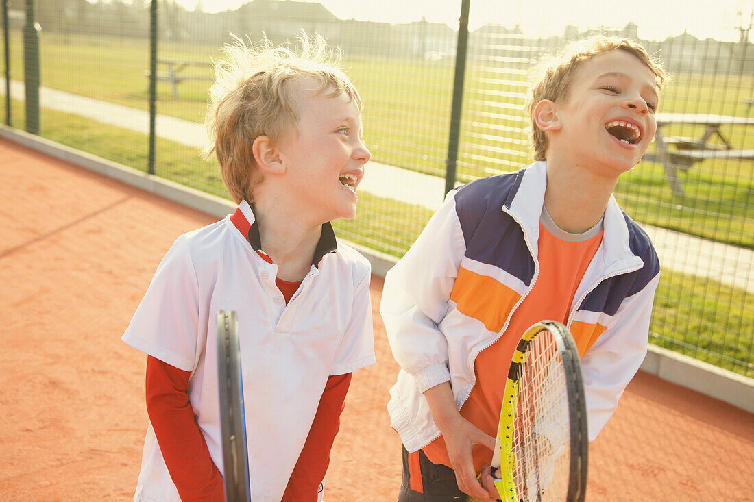 Two Young Boys Holding Tennis Rackets Smiling